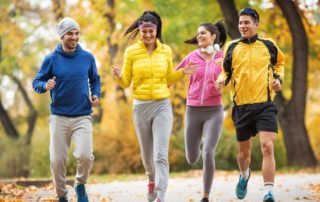 eine gruppe von personen durchschnittlichen alters joggen gemeinsam durch eine baumallee