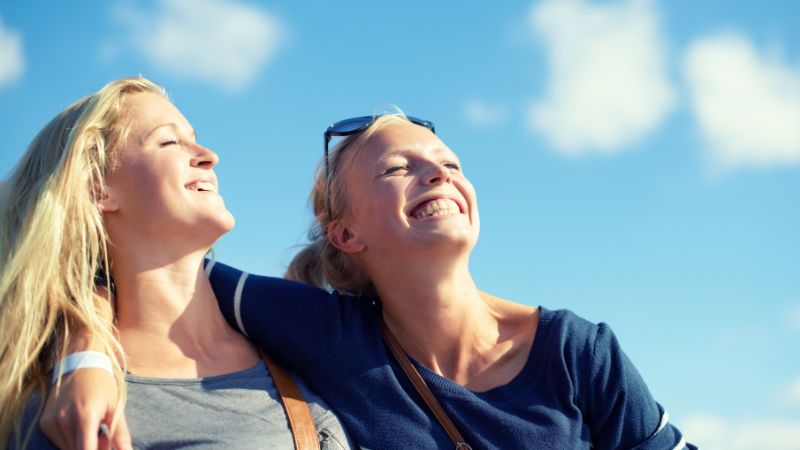 zwei blonde junge mädchen geniessen die sonne