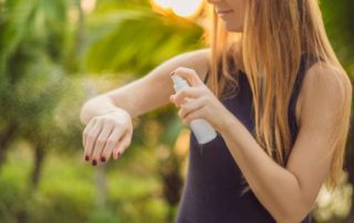 junges mädchen besprüht ihren nackten oberarm mit einem insektenschutzspray