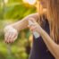 junges mädchen besprüht ihren nackten oberarm mit einem insektenschutzspray