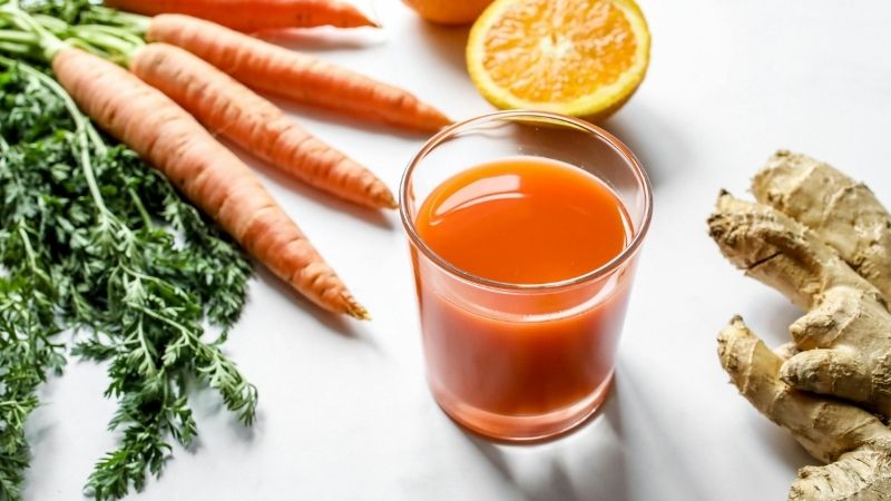 frisches obst und gemüse mit einem vitamindrink liegen auf einer weissen oberfläche